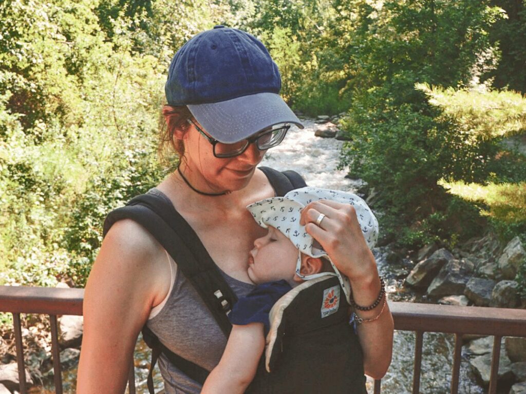 Mom wearing small boy in baby carrier on bridge over a river- family friendly outdoor activities in Petoskey Michigan
