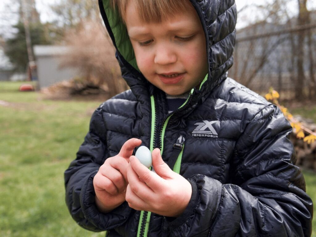 Boy looking at robin's egg that he found on a spring hike. 