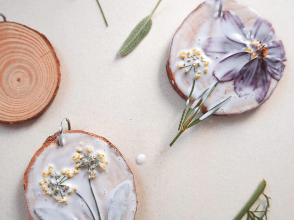 nature craft: small wood slices with flowers laid on top and glue painted over them.  