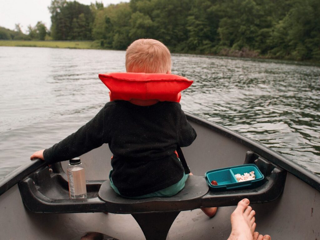 small boy sitting in front of a canoe- summer bucket list