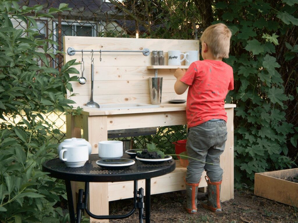 Small boy plays in his mud kitchen