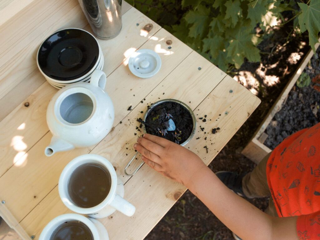 view from above of child's hand making mud pie on counter of mud kitchen