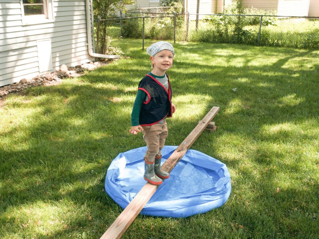 small boy dressed as pirate walks "plank" over kiddie pool while on a treasure hunt