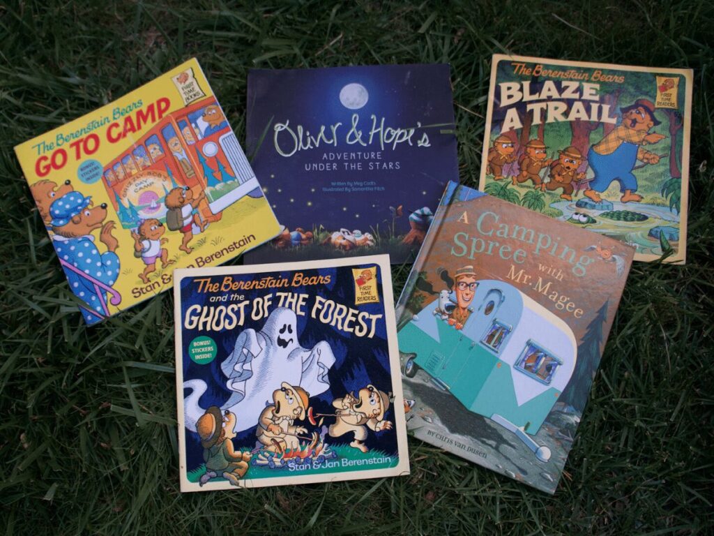 camp themed books spread out on grass to read by campfire