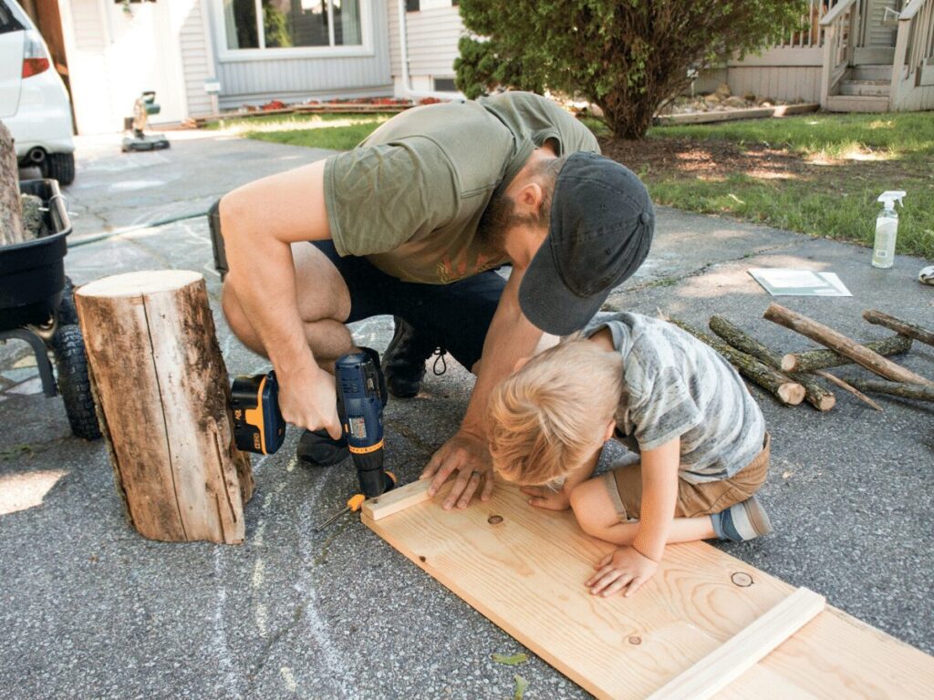 small boy helps dad with power drill while building table- business ideas for kids.
