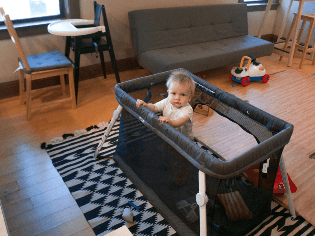 small boy peeks out of pack and play- outdoor gear for babies