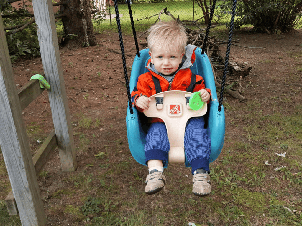 small boy swinging outside- outdoor gear for babies