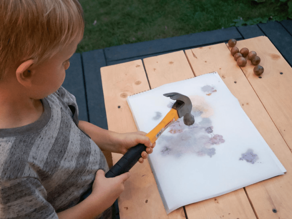 small boy pounding flowers onto paper with hammer- flower crafts