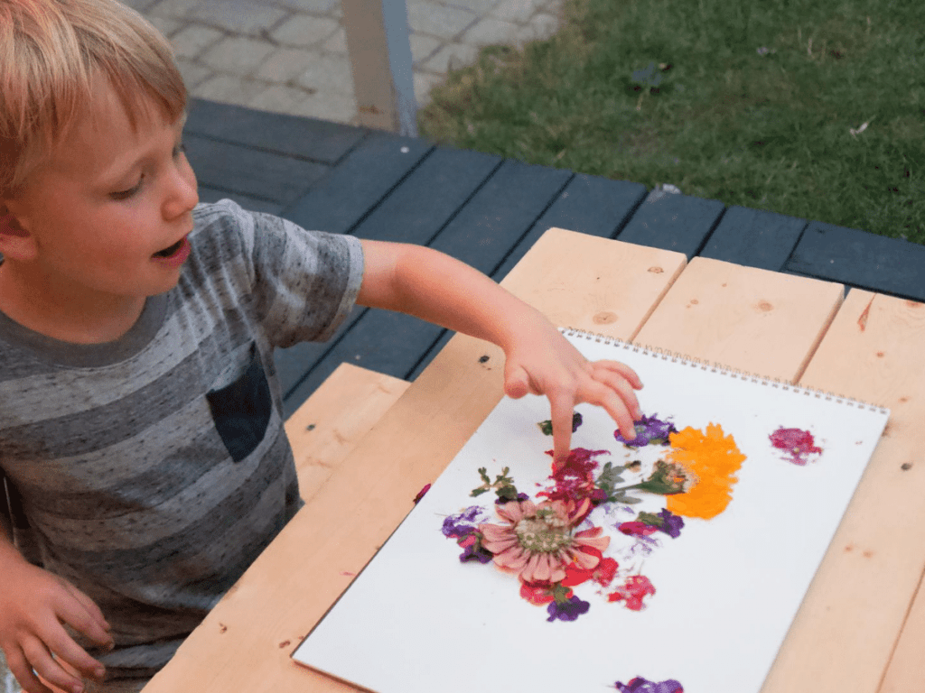  small boy pointing at crushed flowers on paper- flower crafts