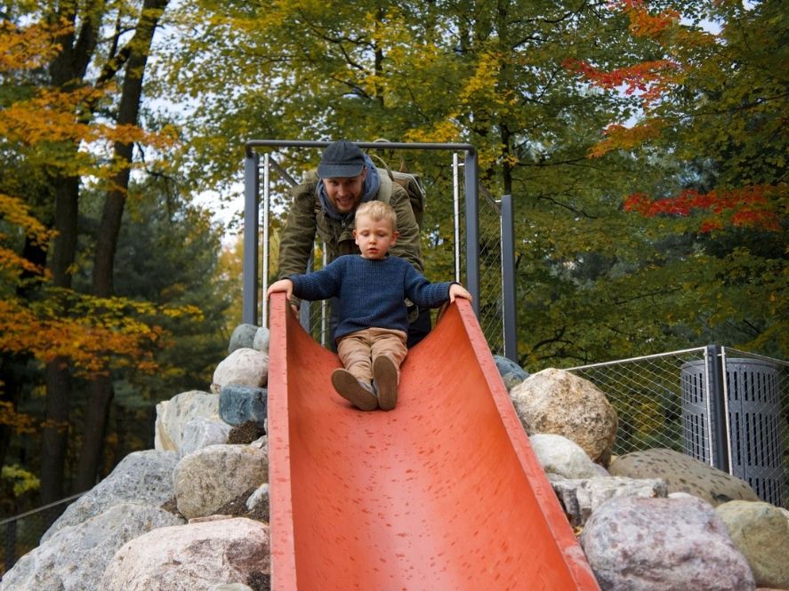 small boy on top of slide at dow gardens playground
