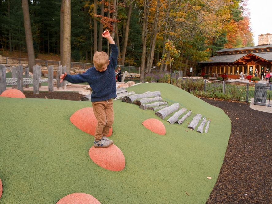 small boy balancing on ball at playground in dow gardens