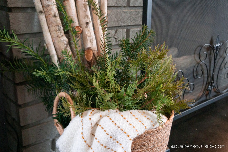 basket with birch logs and greenery next to fireplace
