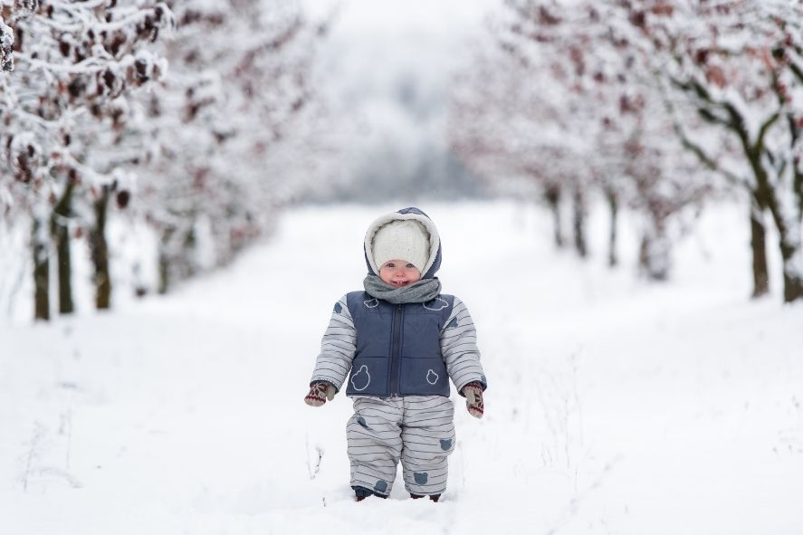 toddler outside in snow wearing puffy snowsuit
