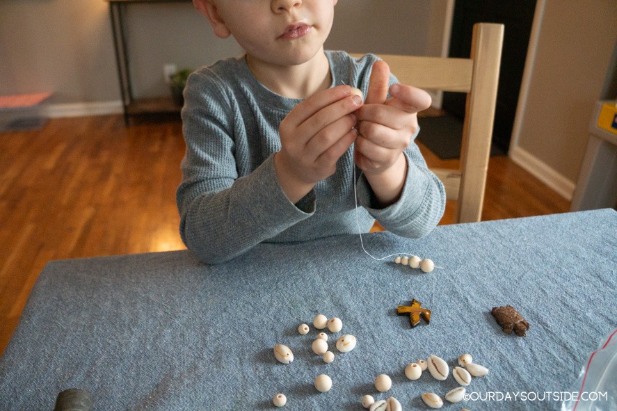 boy stringing beads for diy walking stick