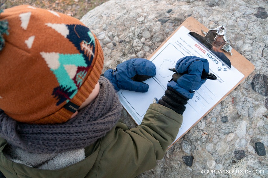 small boy writing on clipboard