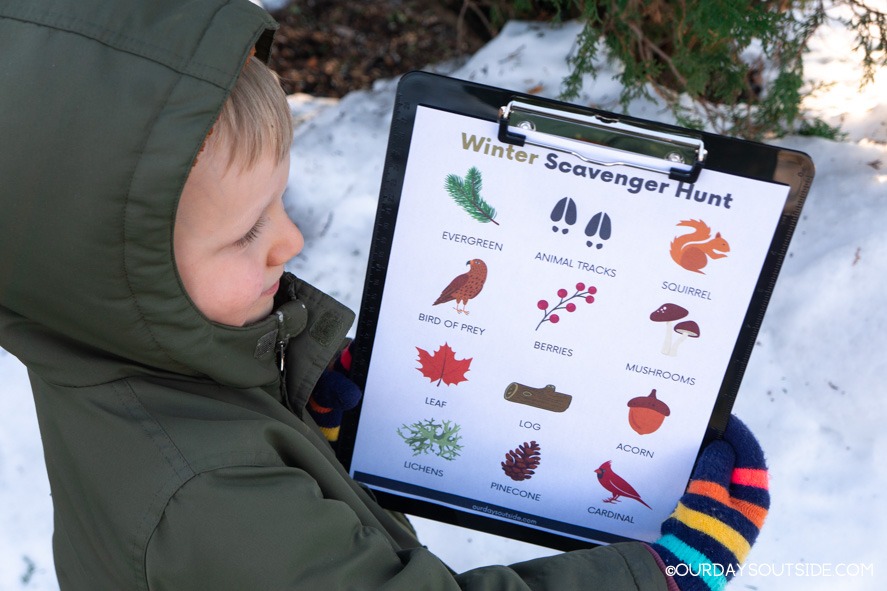 small boy holding winter printable with nature scavenger hunt