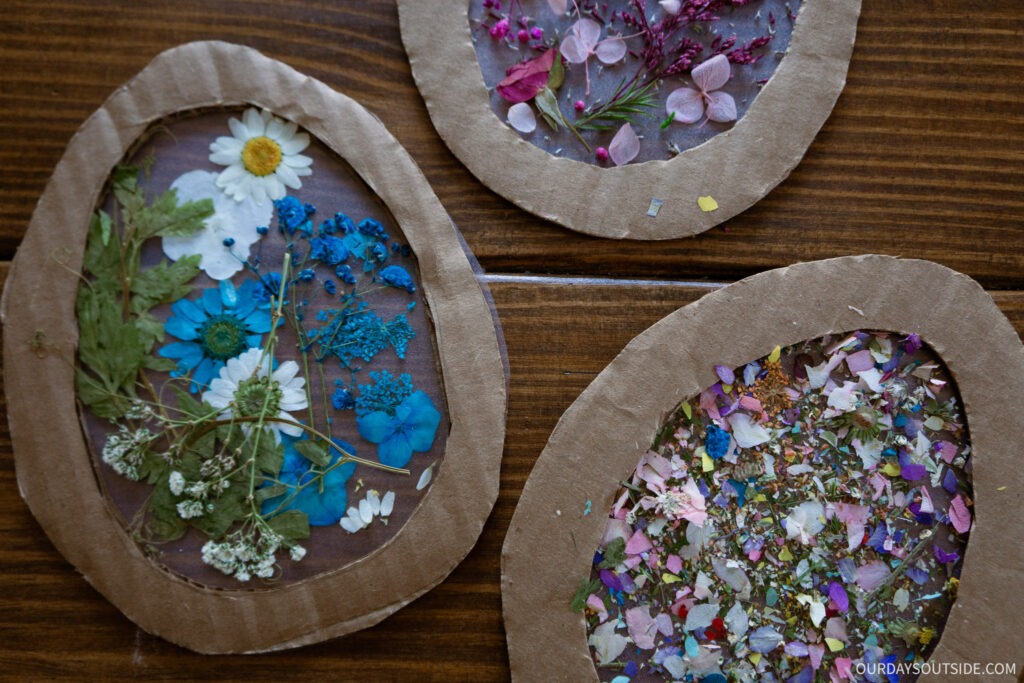 easter crafts and activities: suncatchers the shape of easter eggs with flower decorations in the middle laying on a table 