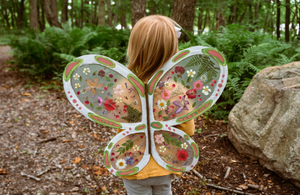 little girl wearing butterfly wings with pressed flowers - nature crafts for kids