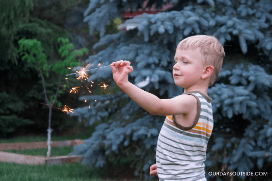 young boy holding sparkler - fourth of july activities